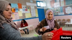 A voter prepares to cast her ballot at a polling station during the second round of the parliamentary election in Tunis, Jan. 29, 2023.