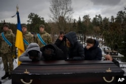 Relatives stand by the coffin of Eduard Strauss, a Ukrainian serviceman who died in combat on January 17 in Bakhmut, during his funeral in Irpin, Ukraine, Feb. 6, 2023.