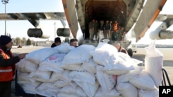 In this photo released by the official Syrian state news agency SANA, workers unload humanitarian aid sent from Arminia for Syria following a devastating earthquake, at the airport in Aleppo, Syria, Feb. 9, 2023.