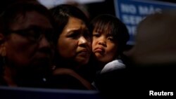 Archivo- Un niño abraza a una mujer mientras la gente sostiene carteles para protestar contra la orden ejecutiva del presidente Donald Trump para detener a los niños que cruzan el sur de EEUU en Los Ángeles, California, el 7 de junio de 2018.