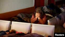 Survivors rest while a woman reacts at a hospital in the aftermath of an earthquake, in Kahramanmaras, Turkey.