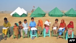 Internally displaced flood-affected children attend a mobile school class near makeshift camp in the flood-hit area of Dera Allah Yar in Jaffarabad district of Balochistan province on Jan. 9, 2023.