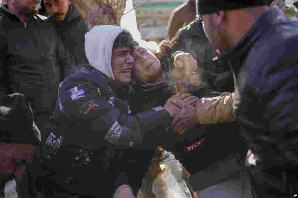The son of Durmus Kilinc, center, reacts after rescue team members removed the dead body of his father from a destroyed building, in Elbistan, Turkey.&nbsp;Tens of thousands of people who lost their homes in a catastrophic earthquake, huddled around campfires in the bitter cold and clamored for food and water, three days after the temblor hit Turkey and Syria.
