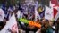 A protester holds a scarf with the word 'teacher' as tens of thousands march down Lisbon's Liberdade Avenue during a demonstration by teachers in Lisbon, Feb. 11, 2023. 