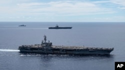 FILE - In a photo provided by the U.S. Navy, U.S. warships sail together in formation, in the South China Sea, July 6, 2020.