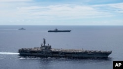 FILE - In a photo provided by the U.S. Navy, U.S. warships sail together in formation, in the South China Sea, July 6, 2020.