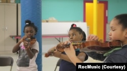 Students practice string instruments with RocMusic in this undated file photo. (Photo courtesy of RocMusic)