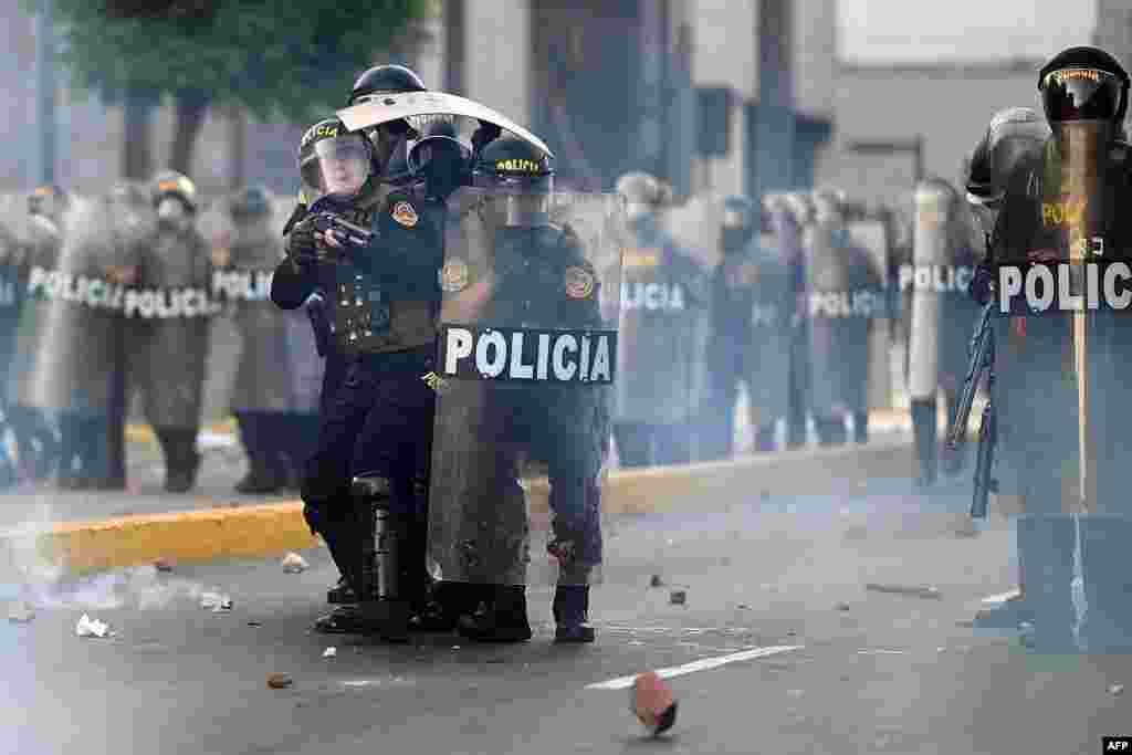 Riot policemen protect themselves from stones thrown by demonstrators during clashes at a protest of the government of Dina Boluarte, in Lima, Peru, Jan. 24, 2023.