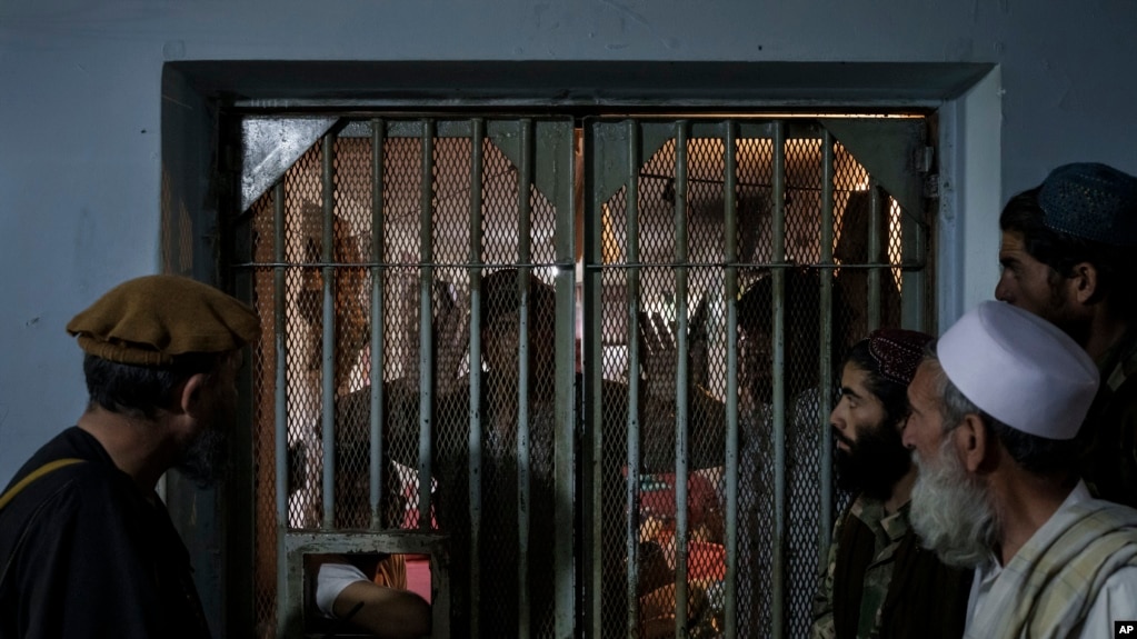FILE - Taliban fighter talk to recently arrested prisoners in the Pul-e-Charkhi prison in Kabul, Afghanistan, Sept. 13, 2021. 