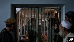 FILE - Taliban fighter talk to recently arrested prisoners in the Pul-e-Charkhi prison in Kabul, Afghanistan, Sept. 13, 2021. 