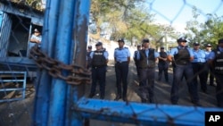 FILE - Police stand guard at the Judicial Assistance Directorate holding center as they face demonstrators, on the other side of the fence, protesting the arrests of anti-government protesters in Managua, Nicaragua, April 25, 2018.