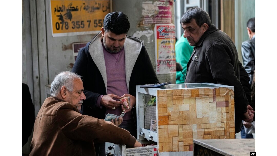 Seorang pria menukar dolar AS di tempat penukaran uang jalanan di pasar utama Shurja, Baghdad tengah, Irak, Sabtu, 14 Januari 2023. (AP/Hadi Mizban)