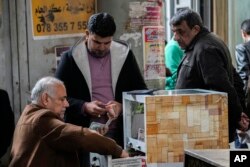 Seorang pria menukar dolar AS di tempat penukaran uang jalanan di pasar utama Shurja, Baghdad tengah, Irak, Sabtu, 14 Januari 2023. (AP/Hadi Mizban)