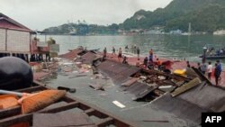 Orang-orang berdiri di atap toko yang runtuh di pelabuhan setelah gempa berkekuatan 5,1 di Jayapura, Papua pada 9 Februari 2023. (Foto: AFP)