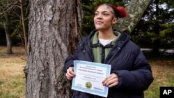 FILE - Kailani Taylor-Cribb holds her GED diploma outside her home in Asheville, N.C., Jan. 31, 2023.