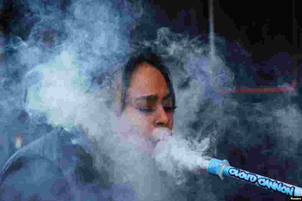 Krys Wolf, a cannabis event joint roller, smokes out of a marijuana cloud cannon on the sidewalk in the Greenwich Village section of New York City, Jan. 24, 2023.