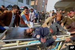 Workers and volunteers carry an injured victim of a suicide bombing upon arrival at a hospital in Peshawar, Pakistan, Jan. 30, 2023.