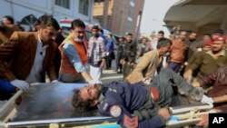Trabajadores y voluntarios cargan a una víctima herida de un atentado suicida al llegar a un hospital en Peshawar, Pakistán, el 30 de enero de 2023.