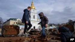 Children stand atop of a destroyed Russian vehicle in the city center of Kyiv, Ukraine, Feb. 2, 2023. 