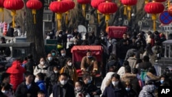 2023年1月30日，中国放弃了对新冠病毒的“零容忍”政策后，北京后海一条熙熙攘攘的街道，传统的三轮儿在人群中穿行。(美联社）