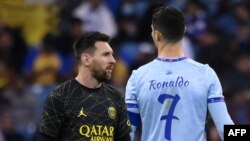 Penyerang Paris Saint-Germain Argentina Lionel Messi (kiri) berjalan melewati penyerang Portugal Cristiano Ronaldo (kanan) selama pertandingan sepak bola di Stadion King Fahd di Riyadh pada 19 Januari 2023. (Foto: AFP)