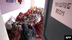 FILE - Afghan women work in a tailoring room of an aid center created by a French NGO, in Afghanistan, Oct. 9, 2001.