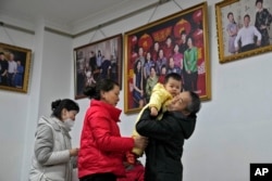 A man carries his grandchild preparing to leave after taking a family photo with his family members at a photo studio in Beijing, Tuesday, Jan. 17, 2023. The world's most populous country has worried for years about an aging population's effect on the economy and society, but the population was not expected to go into decline for almost a decade. (AP Photo/Andy Wong)