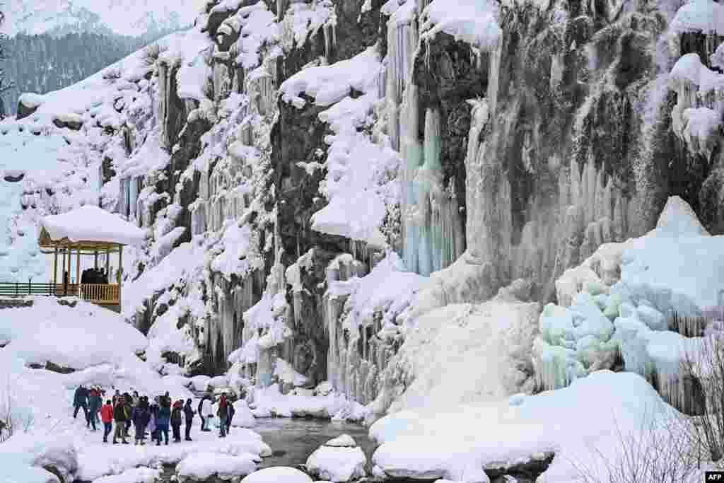 Туристи посетуваат замрзнат водопад во областа Дранг во Тангмар, Кашмир под индиска управа.