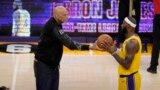 Kareem Abdul-Jabbar, left, hands the ball to Los Angeles Lakers forward LeBron James after passing Abdul-Jabbar to become the NBA's all-time leading scorer. (AP Photo/Marcio Jose Sanchez)