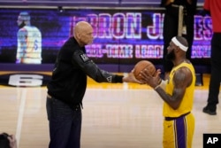 Kareem Abdul-Jabbar, left, hands the ball to Los Angeles Lakers forward LeBron James after passing Abdul-Jabbar to become the NBA's all-time leading scorer. (AP Photo/Marcio Jose Sanchez)