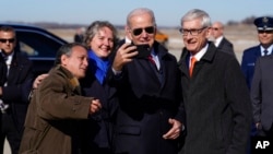 President Joe Biden takes a photo with Gov. Tony Evers, D-Wis., right, after arriving at Truax Field Air National Guard Base, Feb. 8, 2023, in Madison, Wis. Biden was in Wisconsin to promote his economic agenda.
