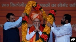 India's western state of Maharashtra Chief Minister Eknath Shinde, right, and his deputy Devendra Fadnavis, left, present a garland to Indian Prime Minister Narendra Modi during a rally in Mumbai, India, Jan. 19, 2023.