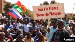 FILE - A protester holds a sign that reads, "France's army get out from our country," as people gather to show their support to Burkina Faso's new military leader Ibrahim Traore, in Ouagadougou, Burkina Faso, Jan. 20, 2023.