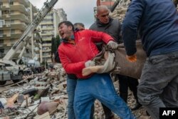 Seorang penyelamat tampak menangis ketika dia membawa mayat yang ditemukan di reruntuhan di Adana pada 6 Februari 2023, setelah gempa berkekuatan 7,8 melanda tenggara negara itu. (Foto: AFP)