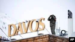 A police officer stands on the roof of a hotel and monitor the area with a binocular in Davos, Switzerland, Jan. 16, 2023. 