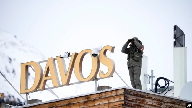 A police officer stands on the roof of a hotel and monitor the area with a binocular in Davos, Switzerland, Jan. 16, 2023.