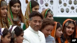 FILE - Pakistani President Gen. Pervez Musharraf and his wife, Sehba, pose with Pakistani children clad in traditional dresses in Islamabad, Pakistan on Aug 14, 2001.