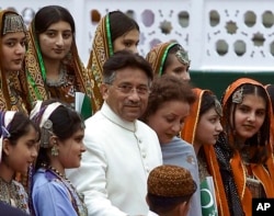 FILE - Pakistani President Gen. Pervez Musharraf and his wife, Sehba, pose with Pakistani children clad in traditional dresses in Islamabad, Pakistan on Aug 14, 2001.