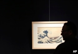 In this Nov. 18, 2016 photo, a visitor photographs "The Great Wave off Kanagawa," Katsushika Hokusai's most well-known work, in the series 36 Views of Mount Fuji during a press preview of the Sumida Hokusai Museum in Tokyo's Sumida Ward.(AP Photo/Eugene Hoshiko)