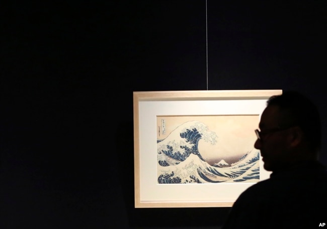 In this Nov. 18, 2016 photo, a visitor photographs "The Great Wave off Kanagawa," Katsushika Hokusai's most well-known work, in the series 36 Views of Mount Fuji during a press preview of the Sumida Hokusai Museum in Tokyo's Sumida Ward.(AP Photo/Eugene Hoshiko)