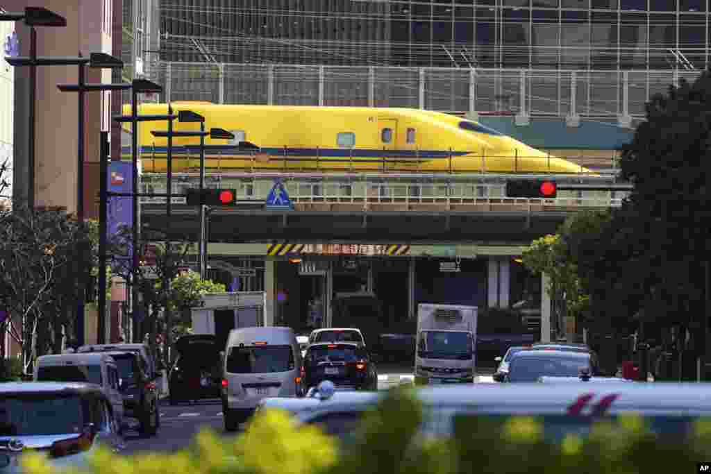 Shinkansen high-speed test trains or known as Doctor Yellow, travels along an overpass in the middle of downtown in Tokyo, Japan.