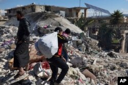 People search through the rubble of collapsed buildings where a newborn girl was found in the town of Jinderis, Aleppo province, Syria, Tuesday, Feb. 7, 2023. (AP Photo/Ghaith Alsayed)