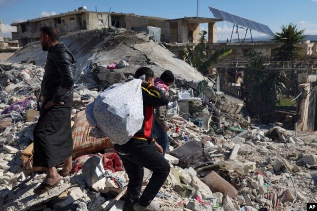 People search through the rubble of collapsed buildings where a newborn girl was found in the town of Jinderis, Aleppo province, Syria, Tuesday, Feb. 7, 2023. (AP Photo/Ghaith Alsayed)