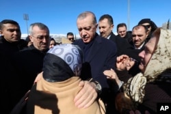 Turkey's President Recep Tayyip Erdogan speaks with a survivor as he visits earthquake-stricken Kahramanmaras, southern Turkey, Feb. 8, 2023.