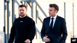 Presiden Prancis Emmanuel Macron, kanan, berjalan di samping Presiden Ukraina Volodymyr Zelenskyy sebelum menuju ke Brussel, di Bandara Militer Villacoublay, di Velizy-Villacoublay, Barat Daya Paris, Prancis, Kamis, 9 Februari 2023. (Foto: via AP)