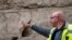 A handout picture provided by the Israel Antiquities Authority on January 25, 2023 shows a Israeli archaeologist pointing at a hand imprint that was discovered carved into a 1,000-year-old dry moat that surrounded Jerusalem's Old City.