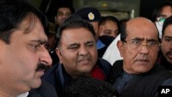 Plainclothes police officials escort Fawad Chaudhry, center, a senior leader of former Prime Minister Imran Khan's party, after his medical checkup at a hospital in Lahore, Pakistan, Jan. 25, 2023. 