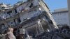 FILE - A woman stand in front of a a collapsed building in Islahiya, in the hard hit region of Gaziantep, Feb. 11, 2023,