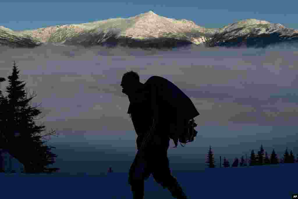 Rob Kenney hikes on Wildcat Mountain across the valley from 5,793-foot Mt. Adams, background, in New Hampshire.