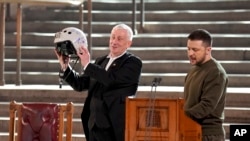 Speaker of the House of Commons, Sir Lindsay Hoyle, left, holds the helmet of one of the most successful Ukrainian pilots, presented to him by Ukrainian President Volodymyr Zelenskyy in Westminster Hall, London, Feb. 8, 2023.
